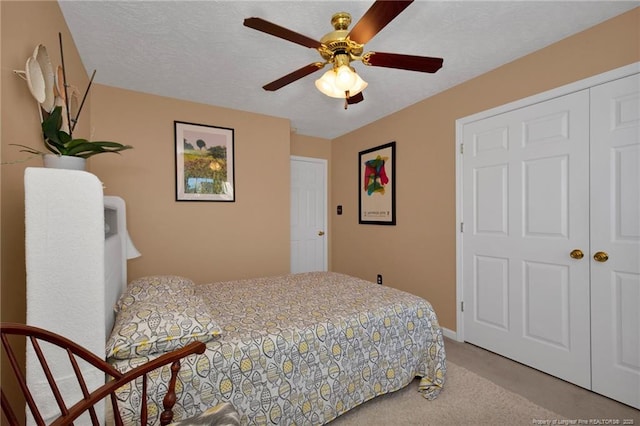 carpeted bedroom with ceiling fan, a textured ceiling, and a closet