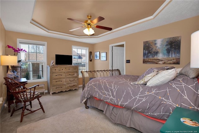 bedroom with a raised ceiling, light colored carpet, and ceiling fan