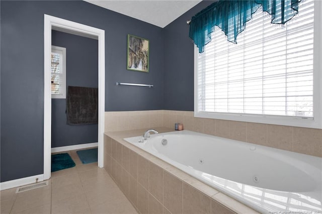 bathroom with tile patterned flooring, a wealth of natural light, and tiled bath