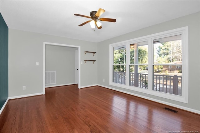 empty room with ceiling fan and dark hardwood / wood-style flooring