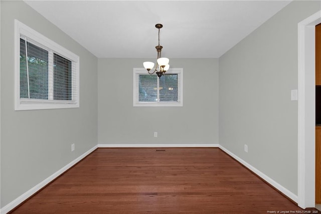 unfurnished dining area with a chandelier and dark hardwood / wood-style flooring