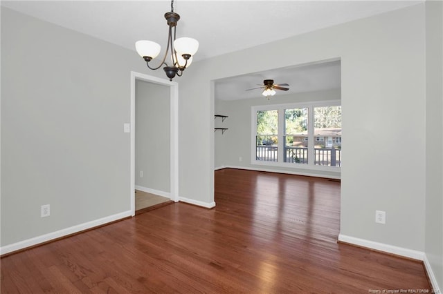 spare room with dark wood-type flooring and ceiling fan with notable chandelier