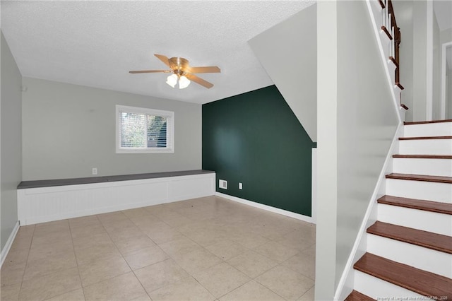 staircase with ceiling fan and a textured ceiling