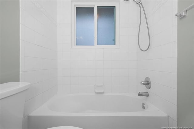 bathroom featuring tiled shower / bath and toilet