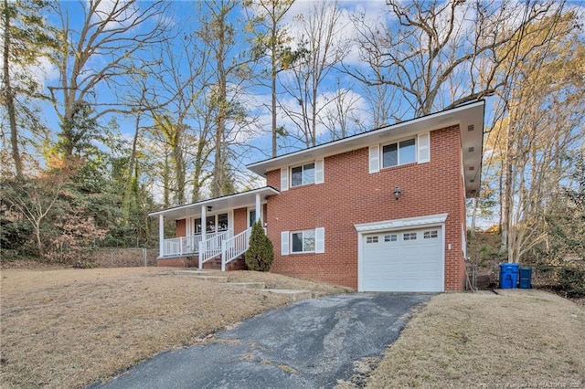 tri-level home with a garage, covered porch, and a front lawn