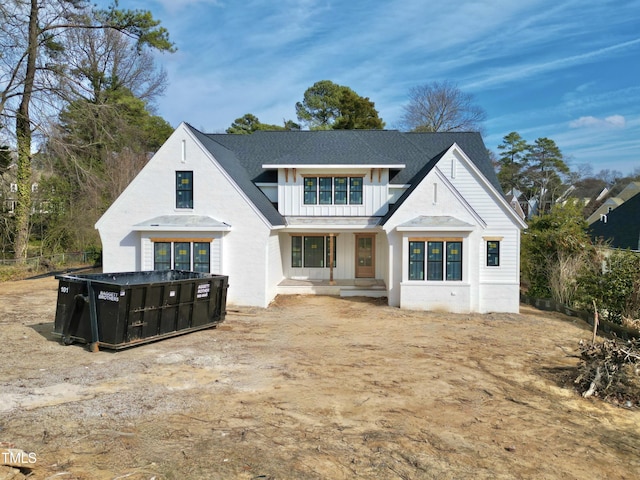 modern farmhouse style home with fence, board and batten siding, and roof with shingles