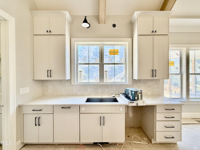 kitchen featuring a sink, beamed ceiling, tasteful backsplash, and light countertops