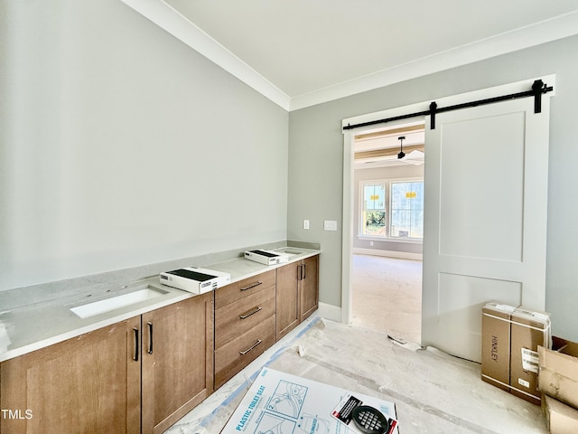 kitchen featuring brown cabinetry, baseboards, ornamental molding, light countertops, and a barn door