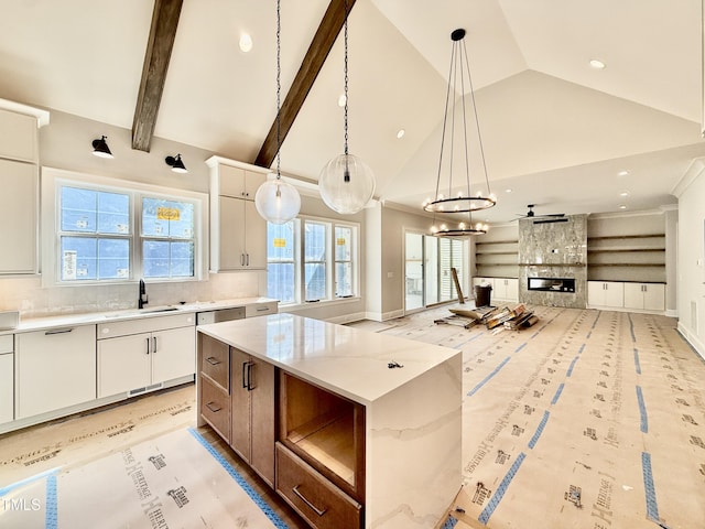 kitchen with white cabinets, a sink, decorative light fixtures, a center island, and open floor plan