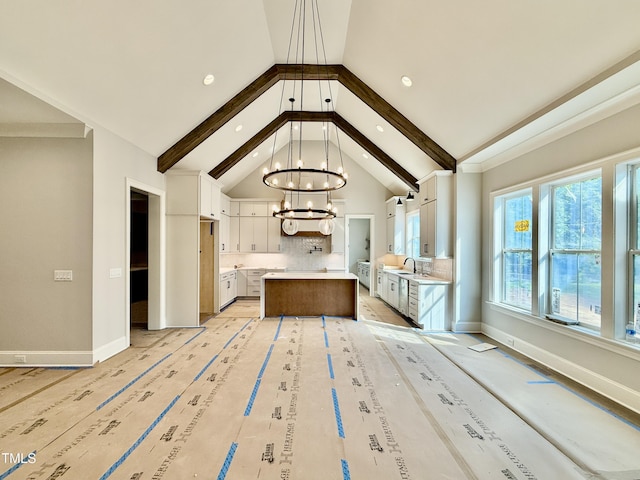 kitchen with a chandelier, light countertops, a kitchen island, and baseboards