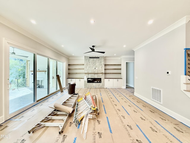 living room featuring ornamental molding, a ceiling fan, visible vents, and a fireplace