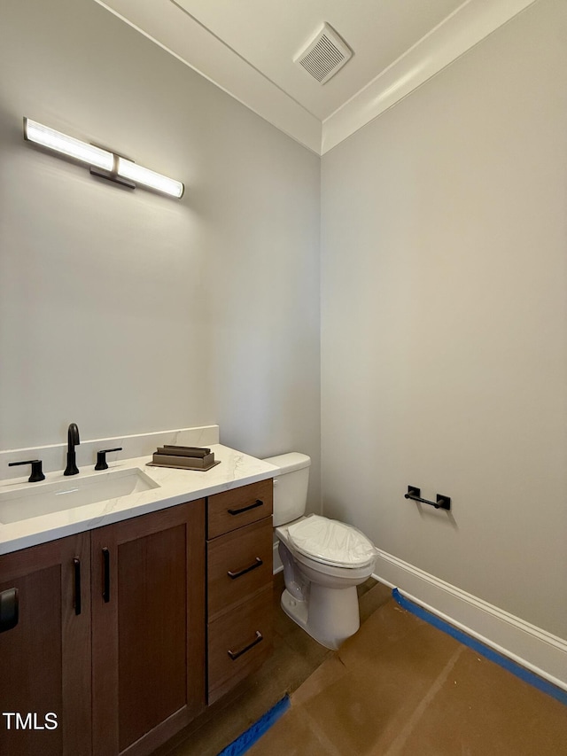 half bathroom with baseboards, visible vents, toilet, and vanity