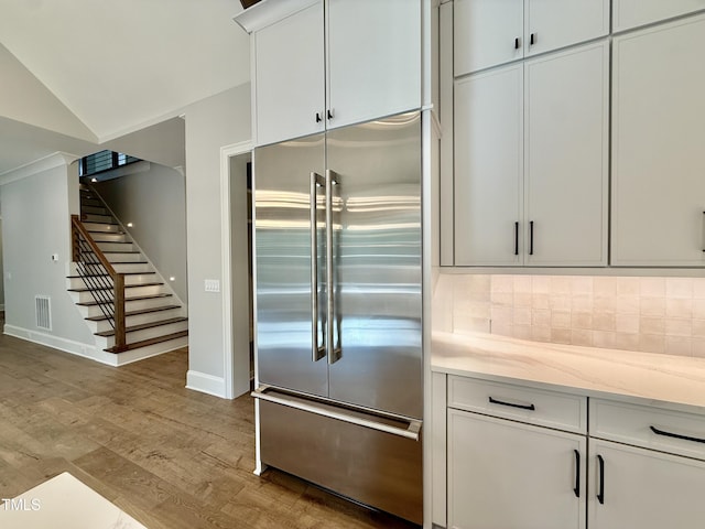 5820 Shawood Dr, Raleigh, NC 27609 - kitchen featuring stainless steel built in refrigerator, wood finished floors, backsplash, light stone counters, and white cabinets