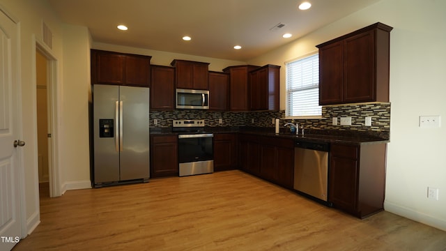 kitchen featuring tasteful backsplash, appliances with stainless steel finishes, sink, and light hardwood / wood-style floors