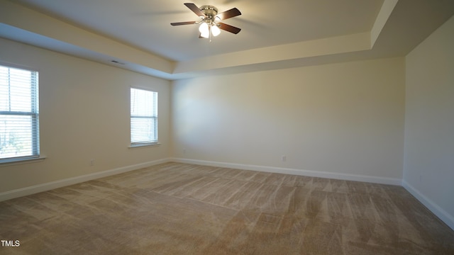 spare room featuring ceiling fan, a raised ceiling, and carpet floors