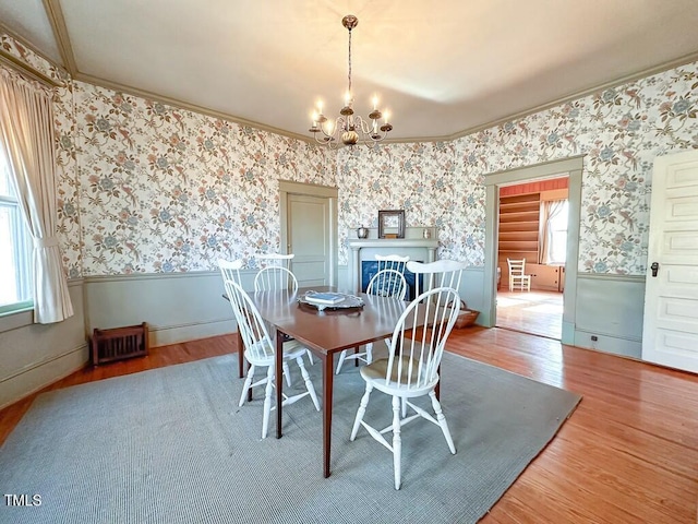 dining space featuring an inviting chandelier, wood-type flooring, and crown molding