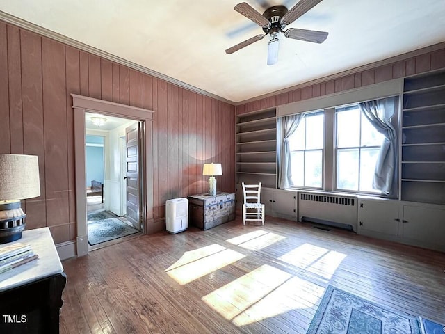 unfurnished room with crown molding, ceiling fan, radiator, and hardwood / wood-style floors