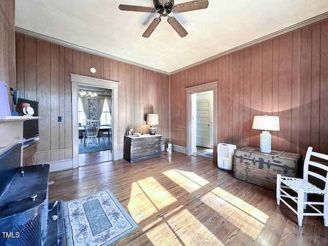 living area featuring hardwood / wood-style floors, ceiling fan with notable chandelier, and ornamental molding