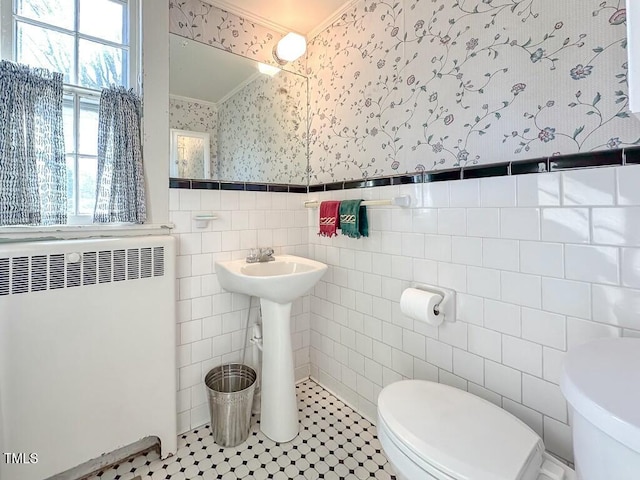 bathroom with crown molding, toilet, radiator, and tile walls