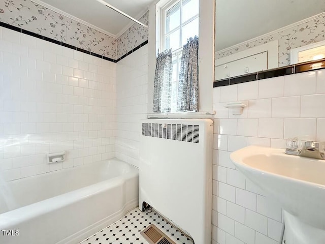 bathroom featuring sink, tiled shower / bath, tile walls, ornamental molding, and radiator