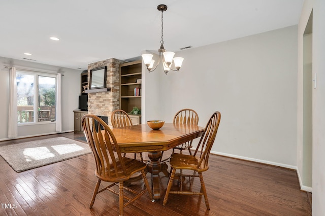 dining room featuring built in shelves, dark hardwood / wood-style floors, and a chandelier