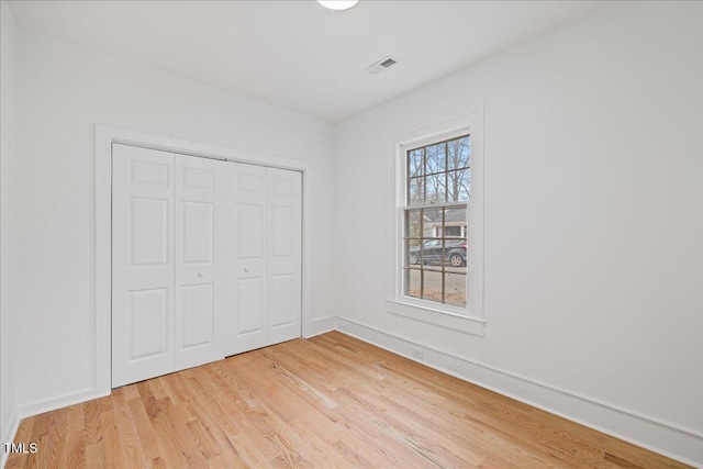 unfurnished bedroom with a closet and light wood-type flooring