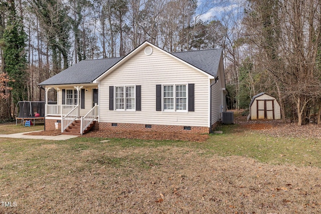 view of front facade with a trampoline, a shed, central AC unit, covered porch, and a front lawn