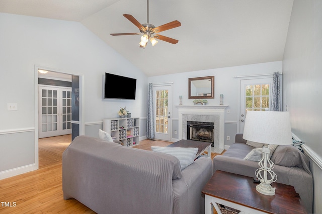 living room with ceiling fan, a premium fireplace, high vaulted ceiling, and light hardwood / wood-style flooring