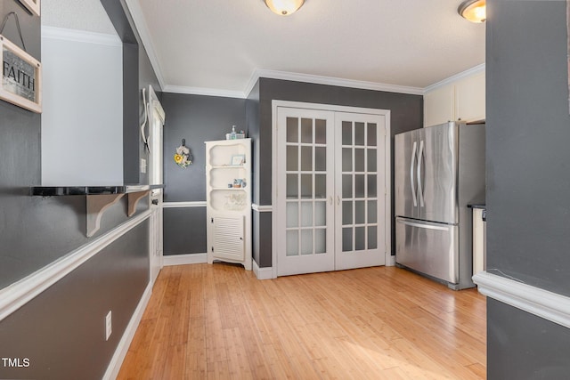 kitchen with crown molding, stainless steel fridge, white cabinets, french doors, and light wood-type flooring