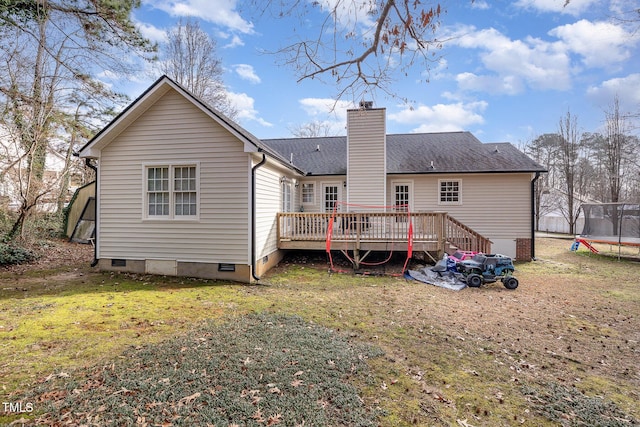 back of house with a trampoline, a wooden deck, and a lawn