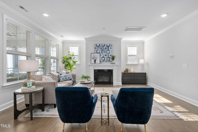 living room featuring hardwood / wood-style floors, crown molding, and a healthy amount of sunlight