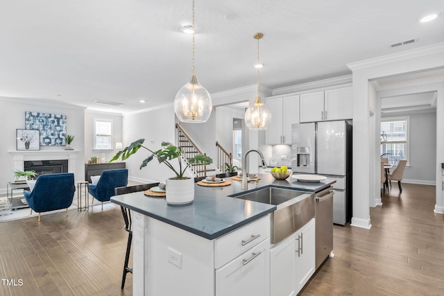 kitchen with sink, white cabinetry, decorative light fixtures, dark hardwood / wood-style floors, and a kitchen island with sink