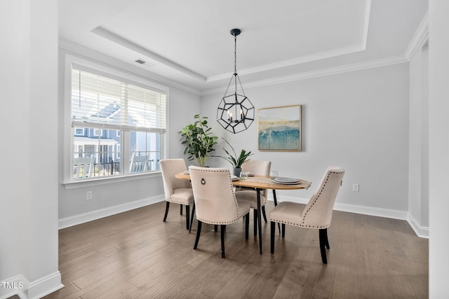 dining area featuring crown molding, wood-type flooring, a raised ceiling, and a chandelier