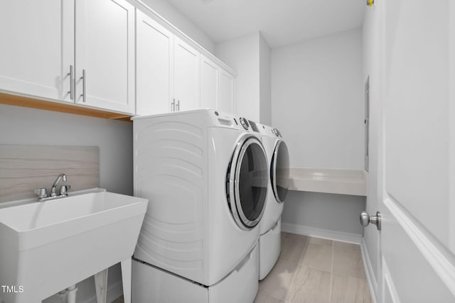 clothes washing area featuring cabinets, sink, and independent washer and dryer