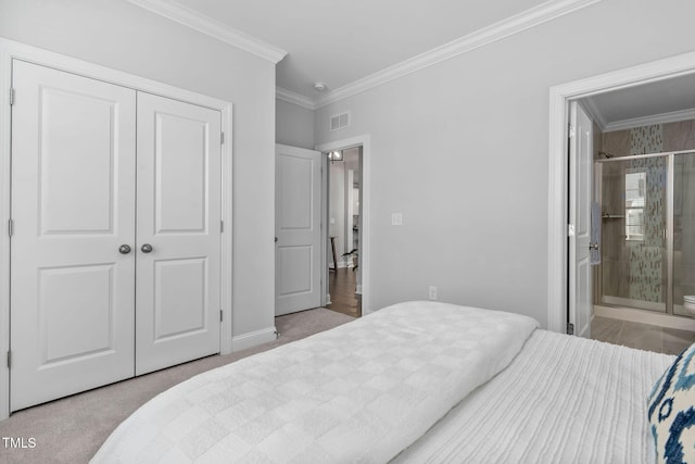 bedroom with crown molding, ensuite bath, light carpet, and a closet