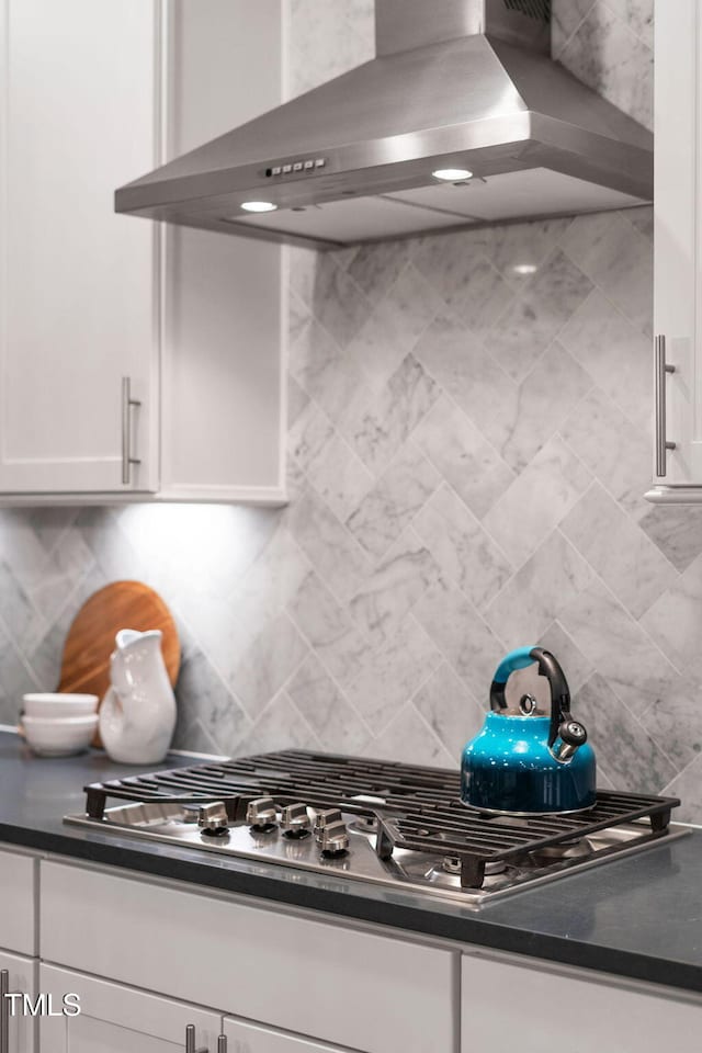 kitchen featuring stainless steel gas cooktop, extractor fan, decorative backsplash, and white cabinets