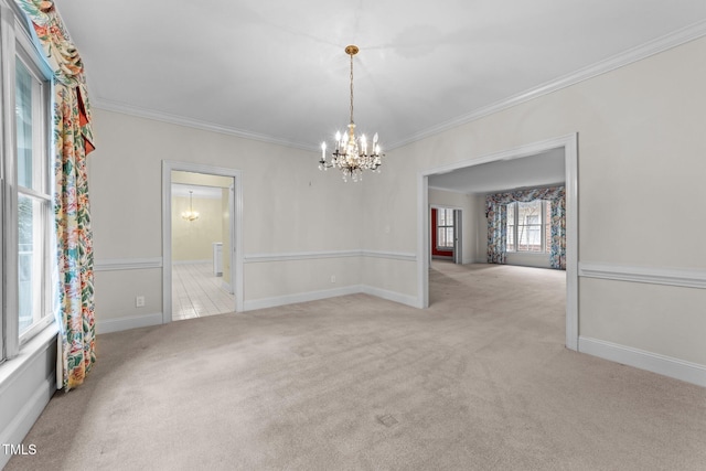 carpeted spare room featuring ornamental molding and a chandelier