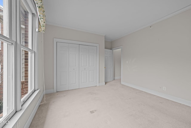 unfurnished bedroom with crown molding, light carpet, and a closet