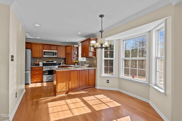 kitchen with appliances with stainless steel finishes, decorative light fixtures, decorative backsplash, ornamental molding, and kitchen peninsula