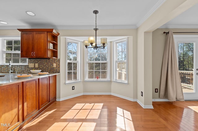 unfurnished dining area featuring a notable chandelier, ornamental molding, and light wood-type flooring