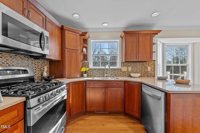 kitchen with sink, decorative backsplash, ornamental molding, light hardwood / wood-style floors, and stainless steel appliances