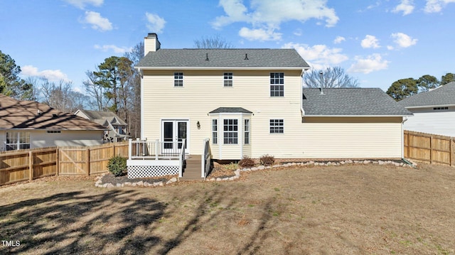 back of property featuring french doors, a wooden deck, and a lawn