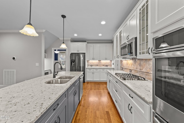 kitchen featuring appliances with stainless steel finishes, pendant lighting, sink, white cabinets, and light stone counters