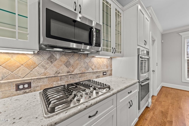 kitchen featuring ornamental molding, appliances with stainless steel finishes, white cabinets, and decorative backsplash