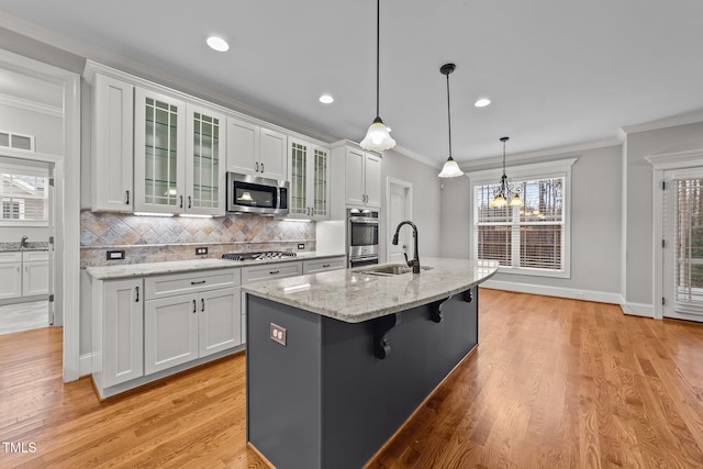 kitchen featuring stainless steel appliances, a kitchen island with sink, sink, and white cabinets