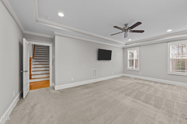 carpeted empty room featuring crown molding, a healthy amount of sunlight, and a tray ceiling