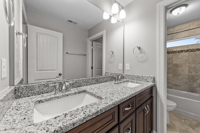 full bathroom featuring tile patterned flooring, vanity, tiled shower / bath, and toilet