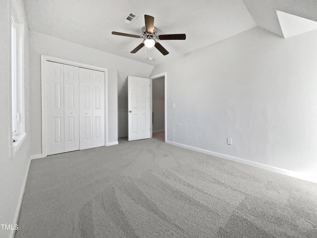 unfurnished bedroom featuring ceiling fan, carpet floors, vaulted ceiling, and a closet