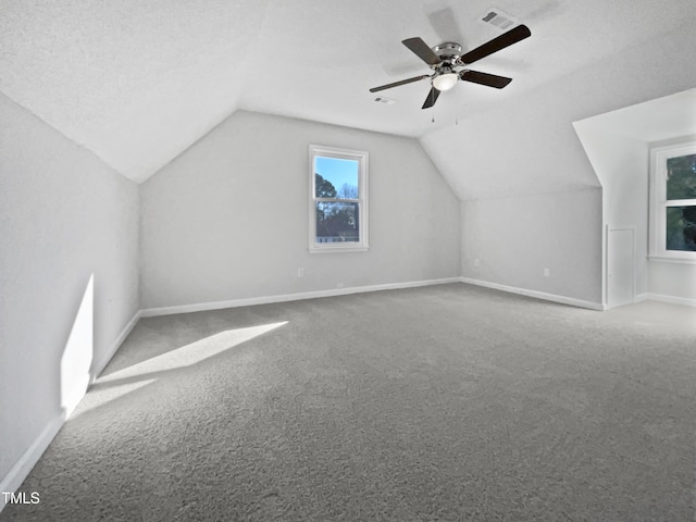 bonus room featuring ceiling fan, lofted ceiling, carpet floors, and a textured ceiling