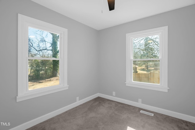 carpeted spare room with ceiling fan and plenty of natural light